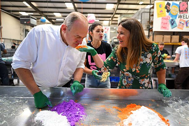 Ed Davey, Leader of the Liberal Democrats and Vikki Slade, Liberal Democrat MP for Mid Dorset and North Poole smell the ingredients as they learn to make bath bombs during a visit to the Lush factory, on July 18, 2025 in Poole, United Kingdom