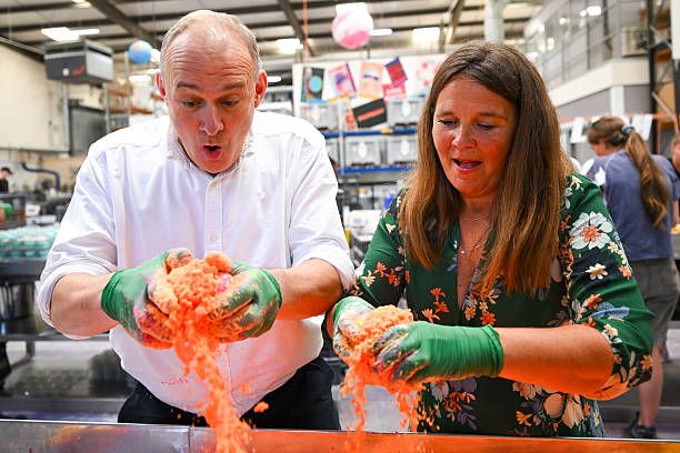 Ed Davey, Leader of the Liberal Democrats and Vikki Slade, Liberal Democrat MP for Mid Dorset and North Poole smell the ingredients as they learn to make bath bombs during a visit to the Lush factory, on July 18, 2025 in Poole, United Kingdom