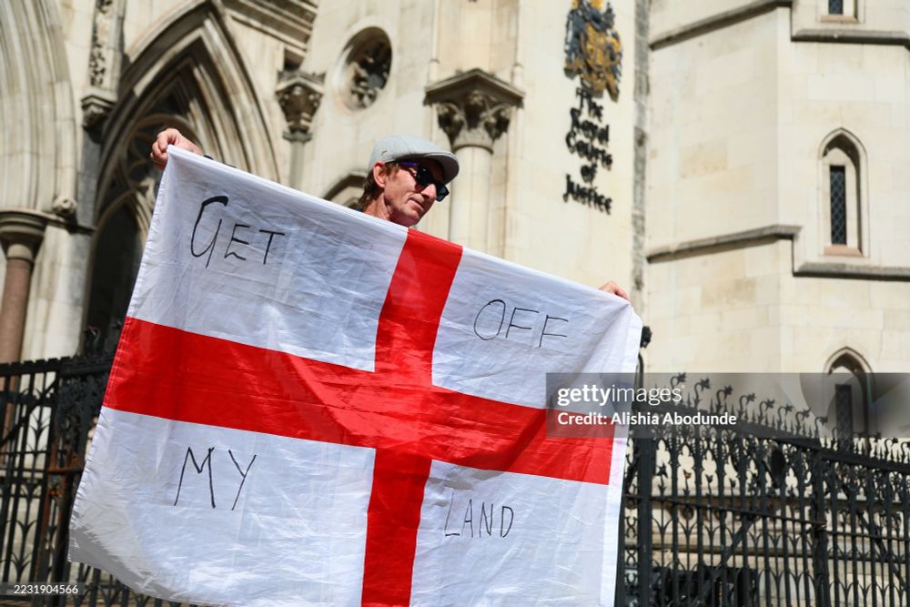 A protester holds the flag of St George with the words 