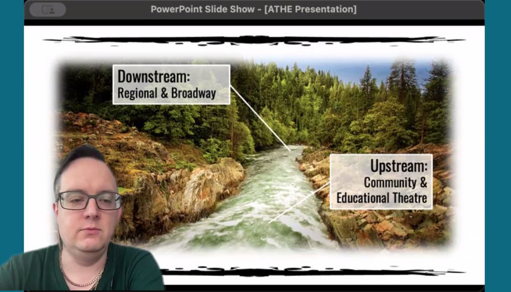 Roblyer presents, arguing for considering "upstream" source of future directors as those working in community and educational theatre that will eventually possibly flow "downstream" to regional and broadway. In the image, Roblyer, a white person wearing a forest green shirt and glasses with an undercut, is in the foreground. In the background, an image of a forest stream with arrows indicating the downstream/upstream ideas described above. 