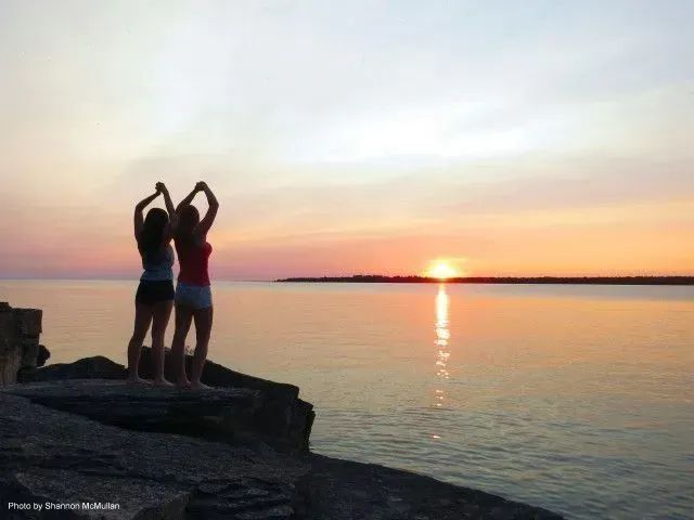 Two girls salute the sunset At Providence Bay on Manitoulin Island.