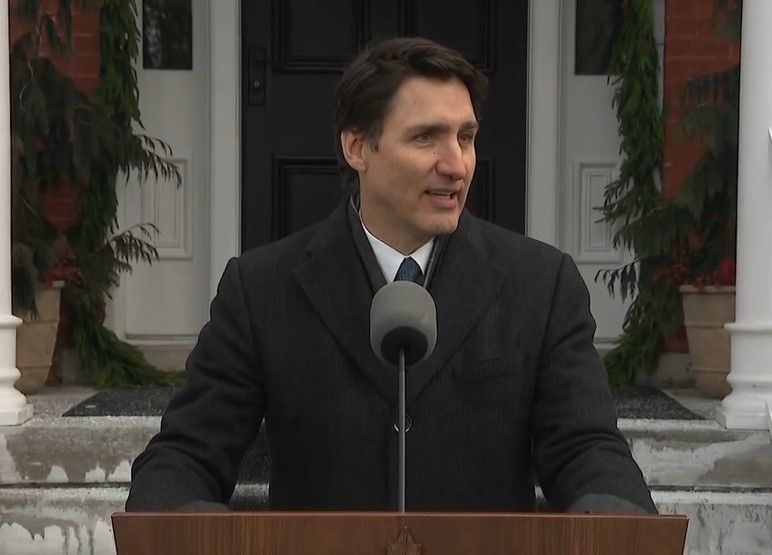 Prime Minister Justin Trudeau stands before a microphone outside his dwelling.