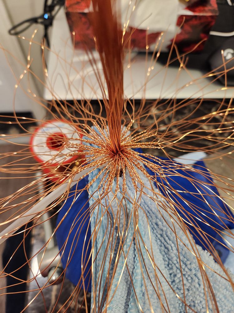 Twisted copper wire branches form a circle around the central bundle. 