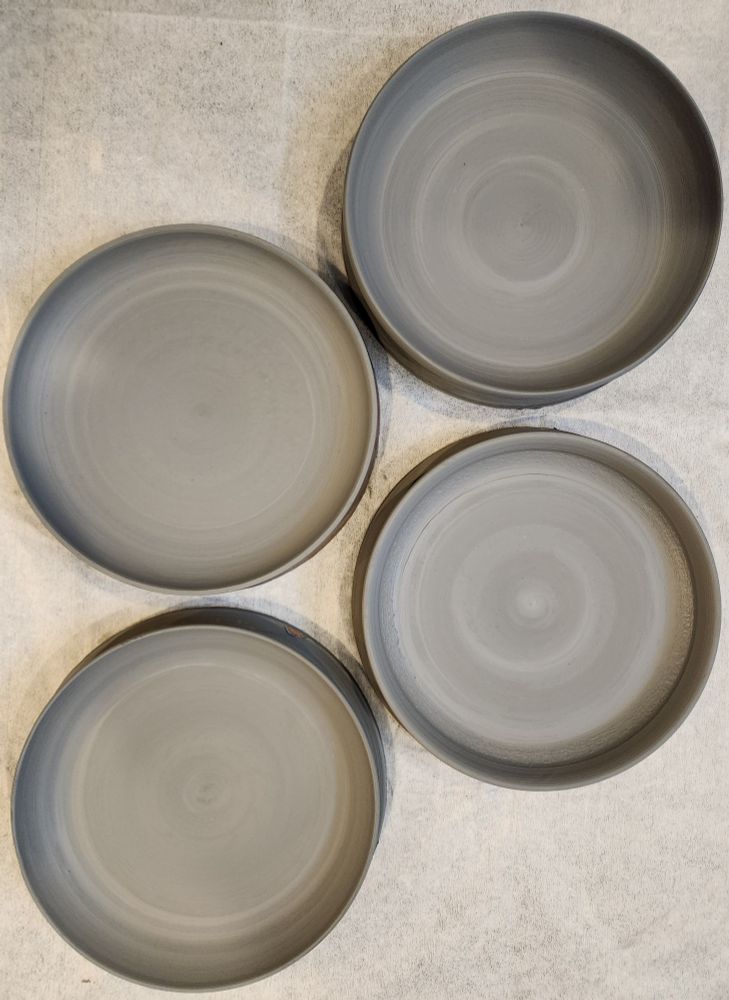 4 grey plates sitting on my workspace, seen from above