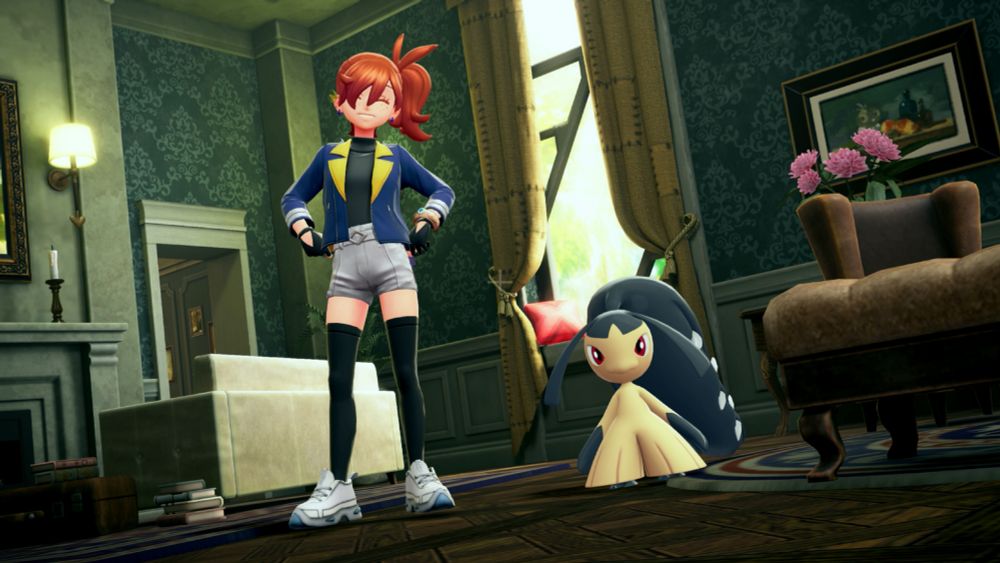 Emm's character beaming with a smile at the camera with their hands on their hips in Pokemon Legends Z-A while standing in a vintage style hotel lobby next to a Mawile.