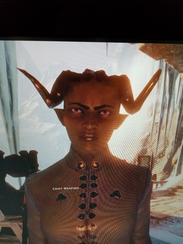 Screenshot taken on phone low quality picture of a female Qunari inquisitor with dark eyebrows and furrowed brow 
