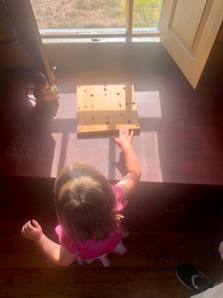 A child looking at a game on a table in the sun