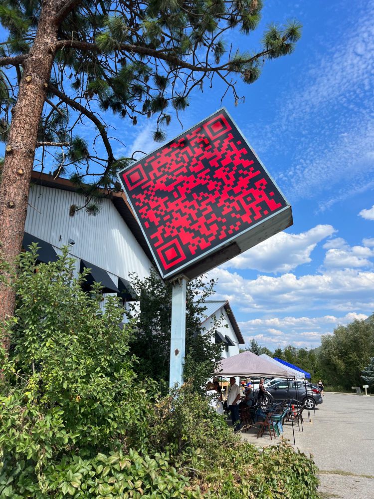 Sign at the entrance of the lot to the Cardiff Miller Art warehouse. It is a large square set on an angle on top of a pole. The sign itself is a smart barcode. 