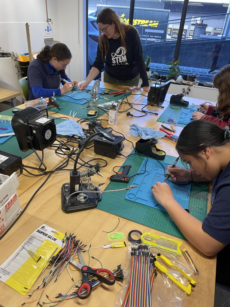 Group of young people working on soldering for a techbug project.