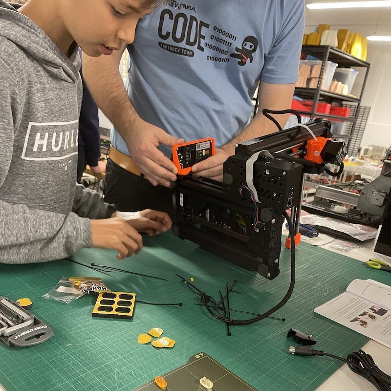 Young person working with an adult on building  Prusa mini 3D printer.
