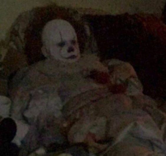 An dark, grainy, low-quality picture of Pennywise the clown lying on some cushions and looking disgruntled