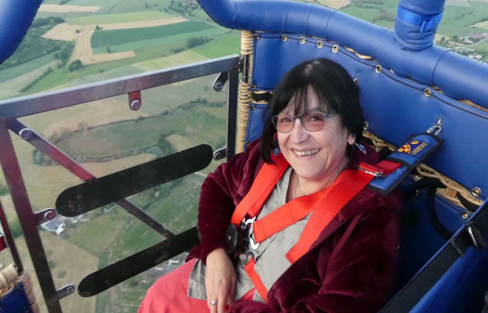 Femme en fauteuil dans la nacelle. Pour faciliter l’accès, HANDI BLUE a été conçu avec une porte en plexiglass qui se transforme en rampe.

Devant la personne assise en fauteuil, l’osier a été remplacé par du plexiglas ainsi elle à une vision devant et sur le côté avec la porte. L’accessibilité en fauteuil manuel ou électrique est complète à la fois pour l’accès à la nacelle avec la rampe et pour le retour à la base avec un véhicule 9 places équipé.

Accessibilité : Accès par une rampe avec le fauteuil de la personne fixé au fond de la nacelle comme dans les véhicules de transport. La personne restera dans son fauteuil afin de rendre l'accès le plus facile possible.