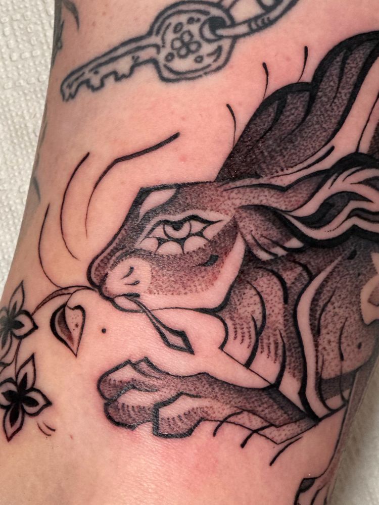 Close-up of the tattoo, with focus on the hares eye, paw and flowery branch.