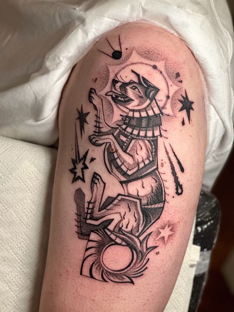 Tattoo on arm showing Laika the space dog in a stylised manner, with stars around her and halo in the back of her head.