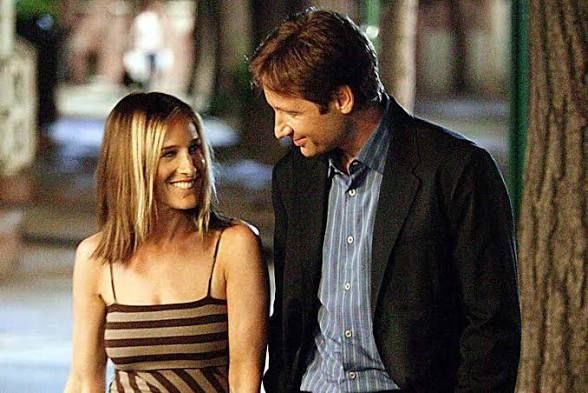 Still from Sex and the City with Sarah Jessica Parker and David Duchovny walking down the street smiling