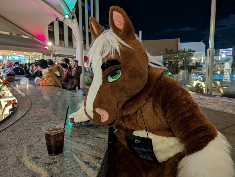 A horse fursuiter staring at a drink at an outdoor bar 