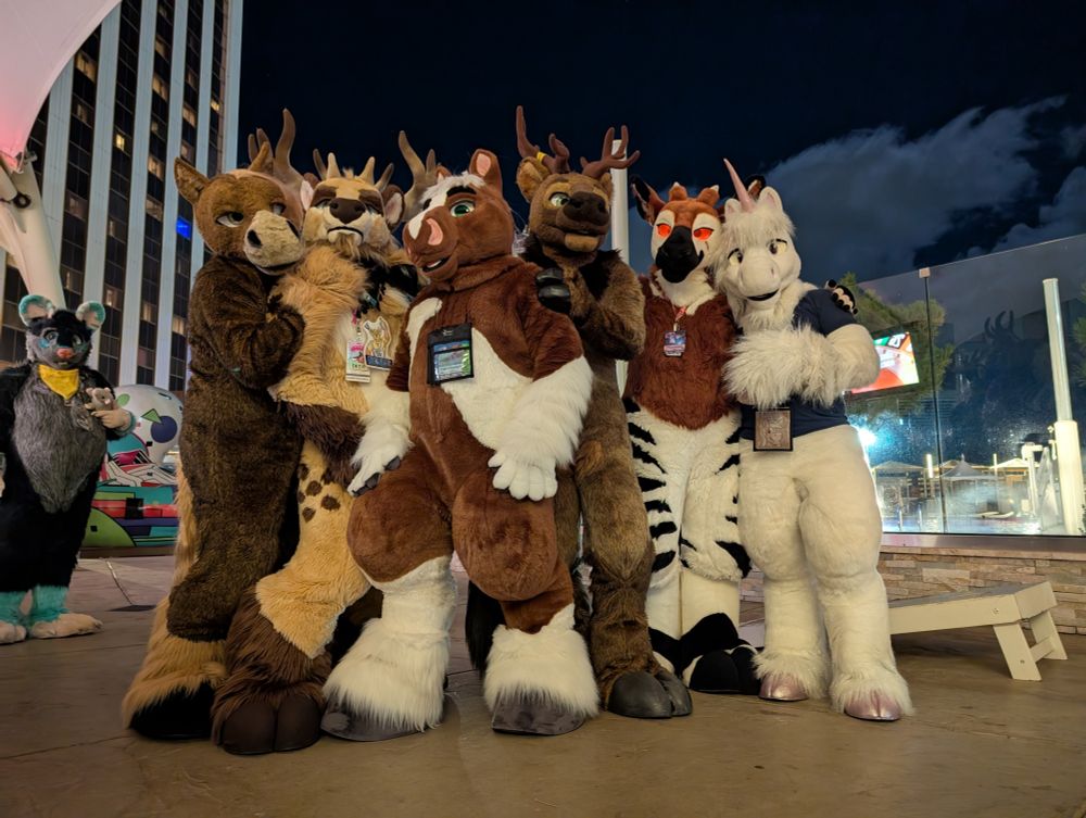 Various hooved fursuits positing for a picture outdoors at night