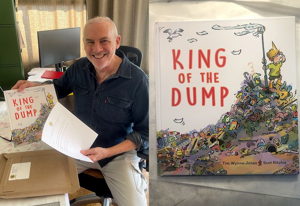 Illustrator, Scot Ritchie, opening up his new copy of King of the Dump. Written by Tim Wynne-Jones and published by Groundwood Books. Art shows a little boy, wearing a crown, climbing to the top of a pile of garbage at the city dump. Colours are bright and fun. 