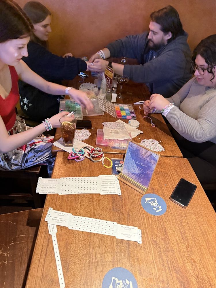Friends sitting at a table making and sharing friendship bracelets 