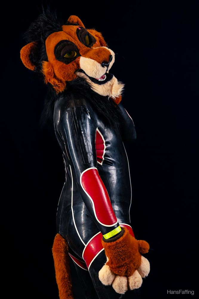 Scar fursuit wearing a rubber catsuit with red details.