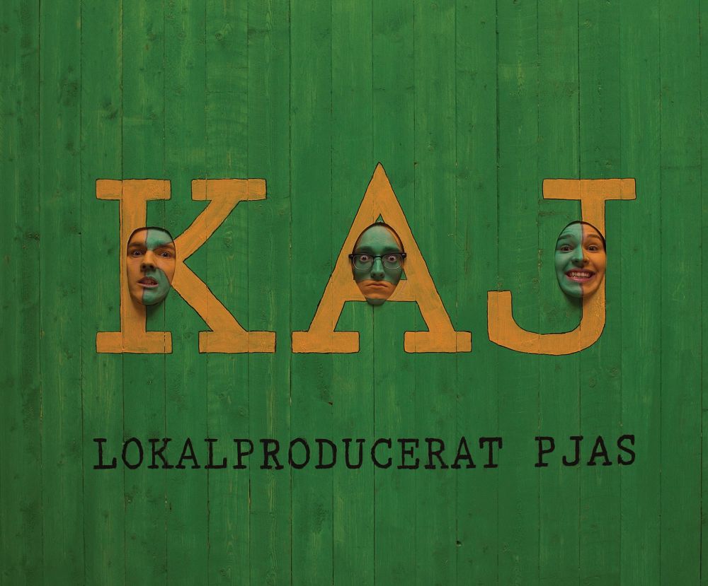 Vihreä albuminkansi yhtyeeltä KAJ ”lokalproducerat pjas”. Yhtyeen jäsenten maalatut päät työntyvät lautaseinän läpi.