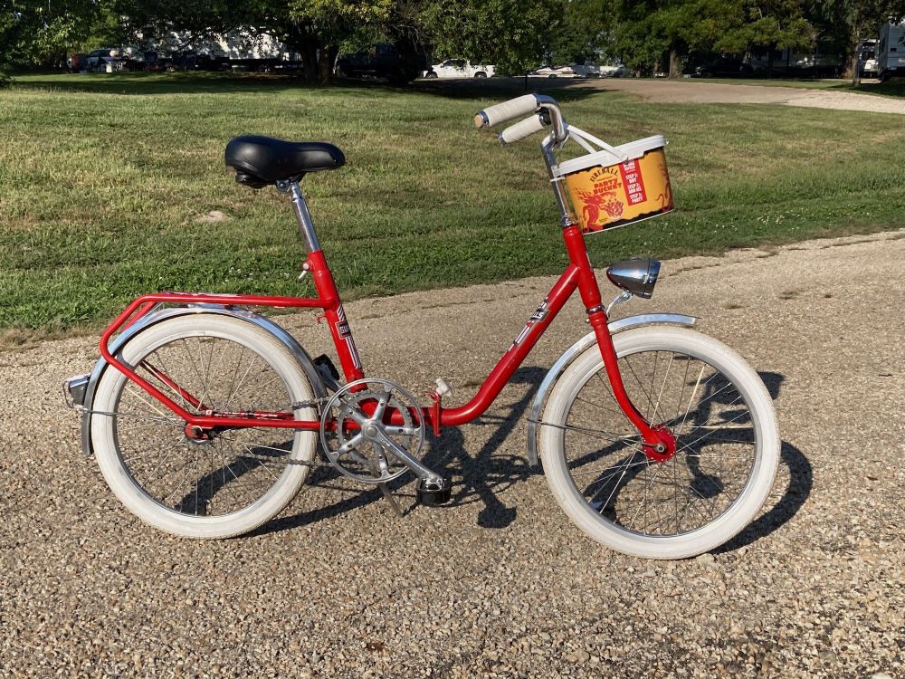 Vintage German folding bike restored in a red and white theme, with a Fireball brand whiskey basket attached to the front.