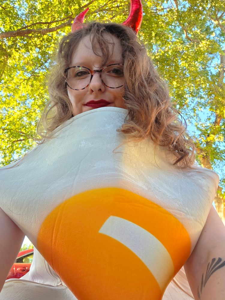 Bluesky user Starry Syndulla in an egg costume with red devil horns. Shes a deviled egg!!
