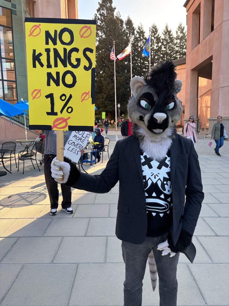 Anthropomorphic rat fursuit holding a sign saying No Kings!