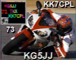 SSTV call sign image featuring a red and white motorbike and rider, turning a corner, knee to the ground.