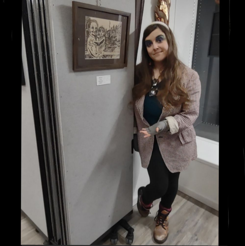 A photo of me, wearing my Dad's blazer, posing next to an illustration I did of him in memoriam, which is an ink drawing with brown ink on brown paper of he and I years ago (him holding me up at the zoo while the seals were behind us).