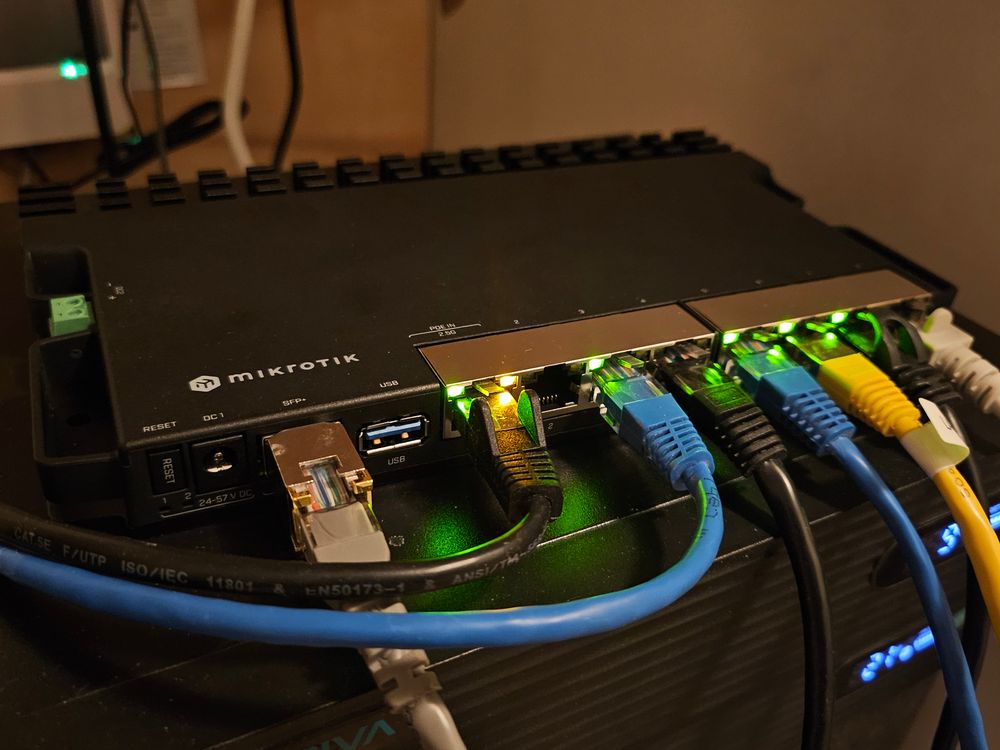 A picture showing a piece of network equipment with various ethernet cables plugged into it. The top of the router pictured says Mikrotik, it's a RB5009. 