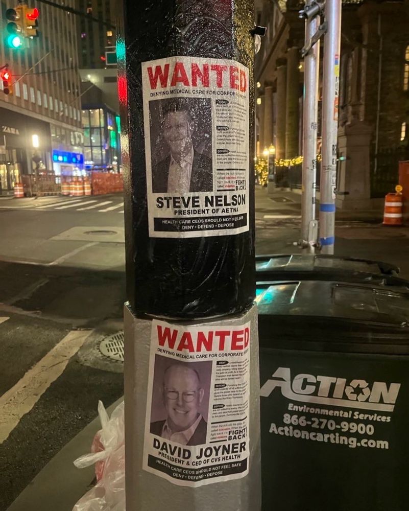 wanted posters on a light post taken at night of Steve Nelson, president of Aetna, David Joyner, president & CEO of CVS Health. Both feature photos of the execs with three bullets labeled DENY, DEFEND, DEPOSE detailing the wrongs of the healthcare industry (but not legible enough in the picture to transcribe).


“Healthcare CEOs should not feel safe. Deny - Defend - Depose” it says at the bottom.