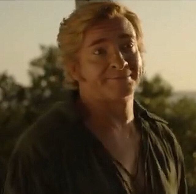 Still from a BTS video Samba shared from season 2 episode 8 of Our Flag Means Death. Stede Bonnet is looking at Ed (not in frame) with his brows slightly raised and a loving smile. He’s wearing an open deep green shirt and the sun is shining on his face.