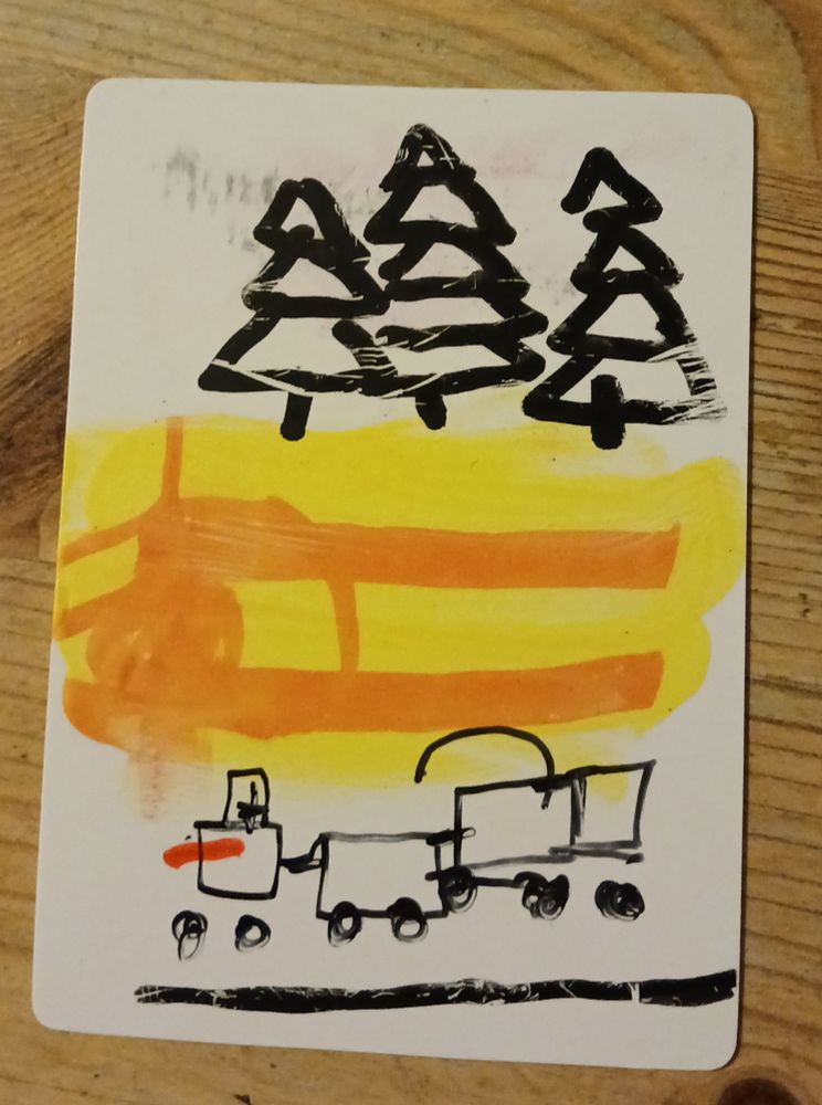 Eine ATC im Hochformat. Sie zeigt drei Tannen im Hintergrund und eine Eisenbahn im Vordergrund. Gelb, orange, schwarz.