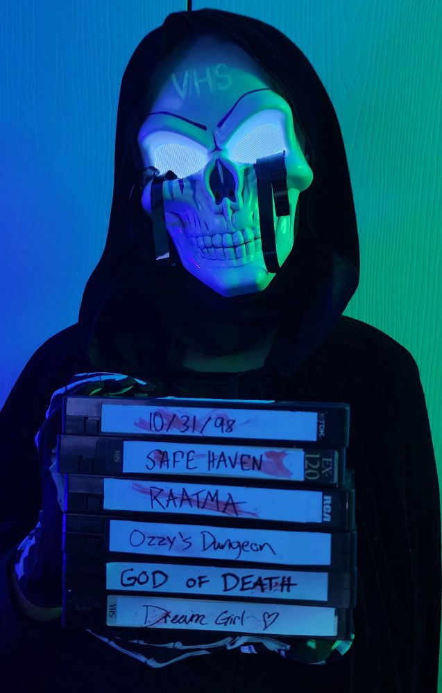 Wearing my V/H/S franchise inspired Halloween costume, holding vhs tapes with segment titles from previous V/H/S films
