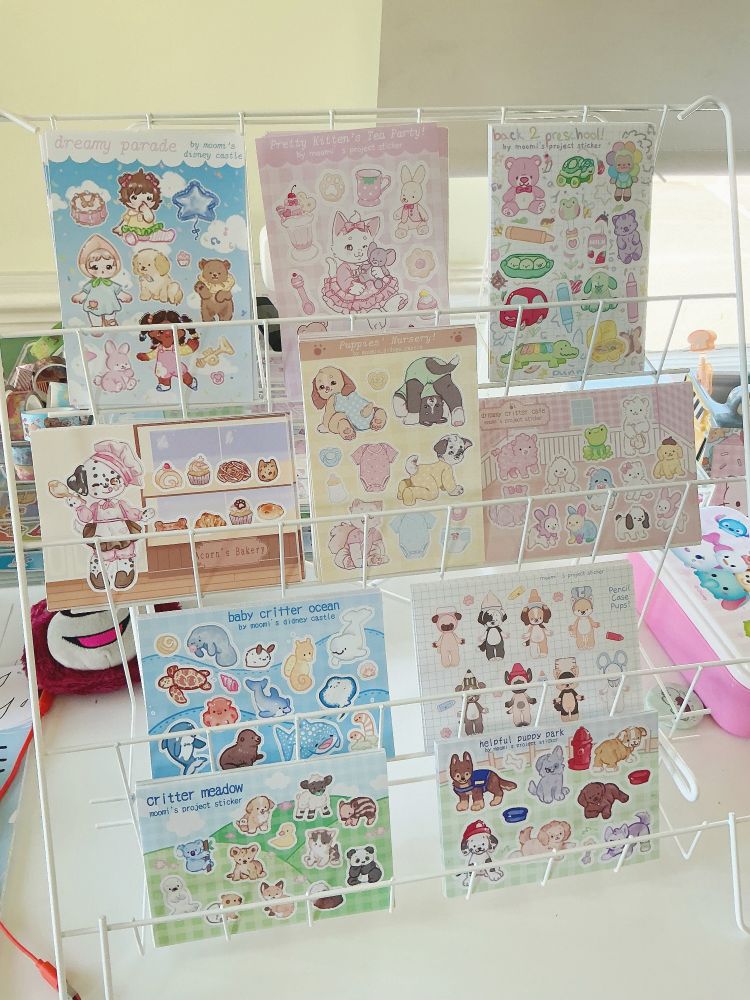 A photo of a big shelf full of stickers. There are four shelves, each full of sheets of stickers featuring cute babyish stickers!