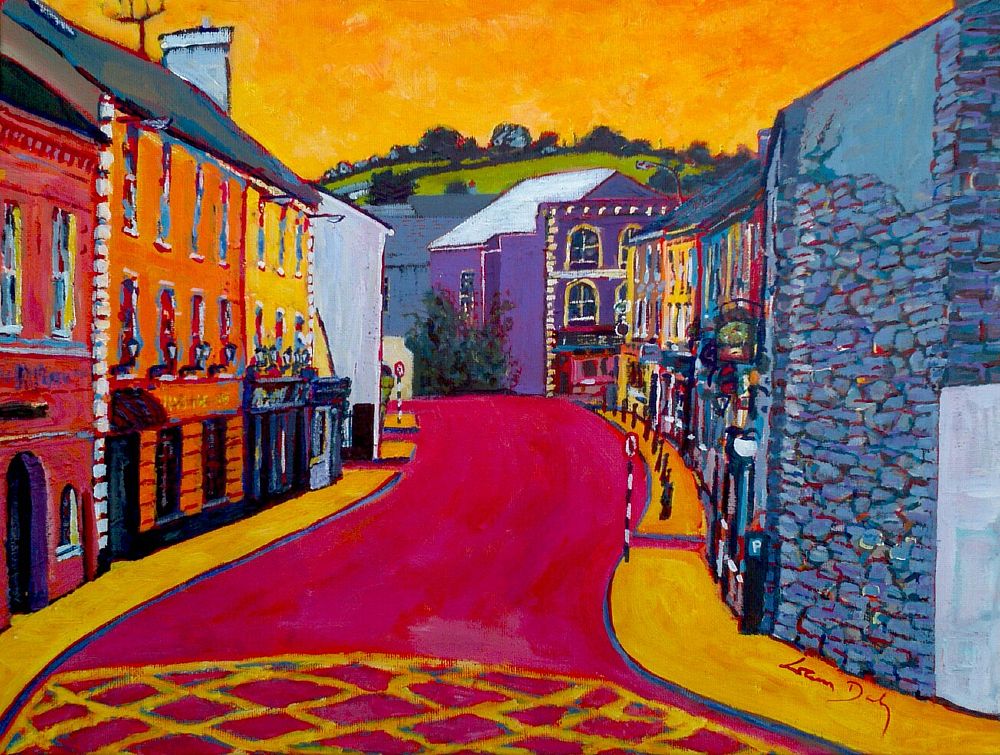 Landscape format in bright acrylics on canvas. View down a slightly curving street. Buildings on left side are 3 storeys of pink, then orange, then yellow, with shop fronts at street level. Rest of left side is hidden as street curves behind a pale grey gable. Right side is aligned with viewing point so buildings are barely visible thin strips of yellow, blue, red, brown, and in foreground on right there is a high grey stone wall with flecks of red, blue and yellow in between the stones. Road surface is a bold pink with yellow box markings along bottom edge of painting; footpaths are bright yellow with blue kerbs. The sky is a painterly yellow. At the end of the street a short distance beyond a front-facing purple building with yellow corner-stones and window arched surrounds, is a rounded green hill with dark hedgerows. Signed bottom right in red on yellow pavement, Liam Daly