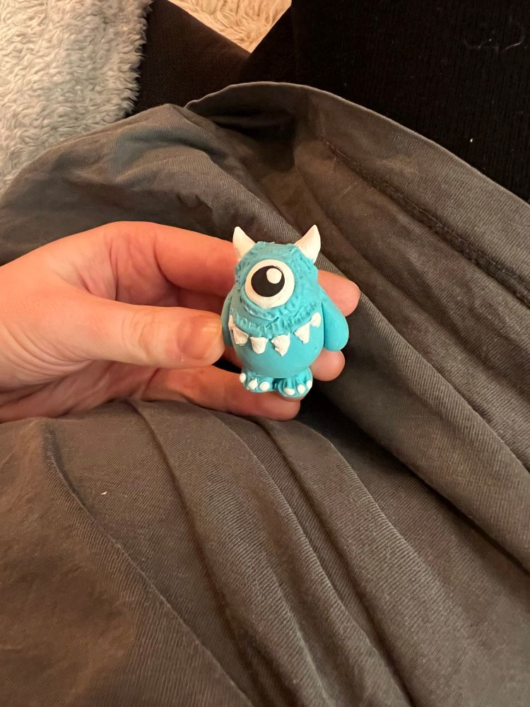 Ein kleines blaues Monster. Es ist Einäugig, hat Hörner, Zähne und ist hellblau.