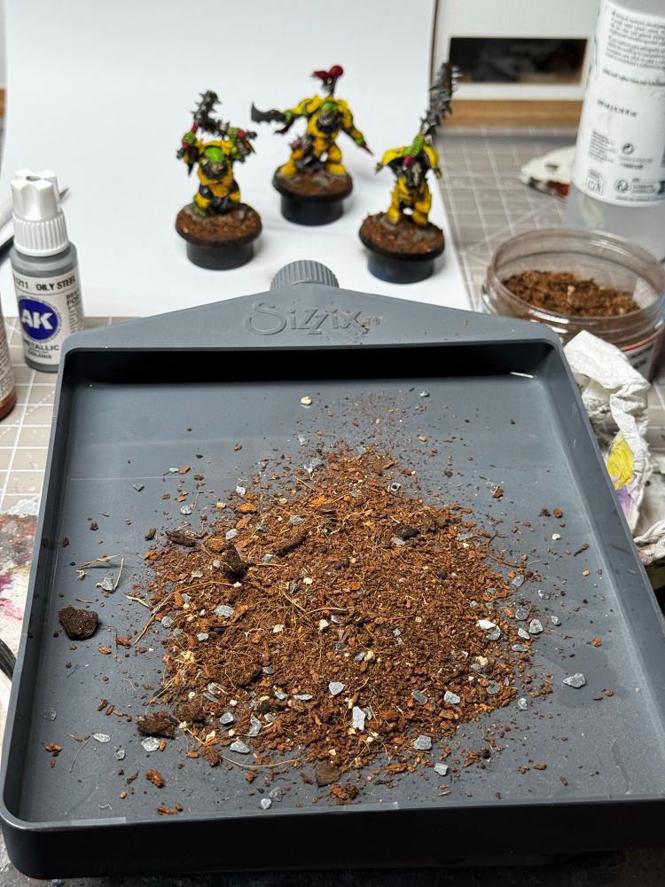 A glitter tray, full of basing material, with some Orruks in the background.