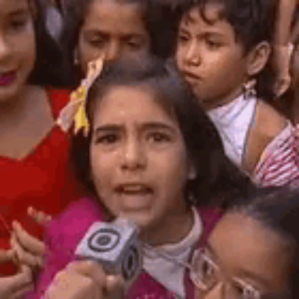 a girl is holding a microphone in front of a group of children .