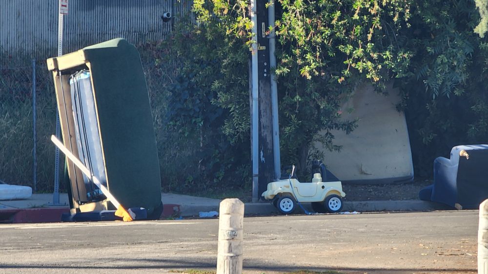 Little white car sized for a child to sit in
 By road. Between 2 couches.
