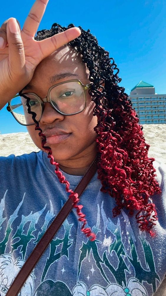 Black woman with red crochet braids at the beach 