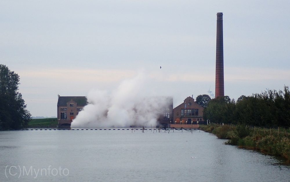 Stoom gemaal bij Lemmer in bedrijf. Rechts een hoge schoorsteen, in het midden het gebouw met stoom wolken.