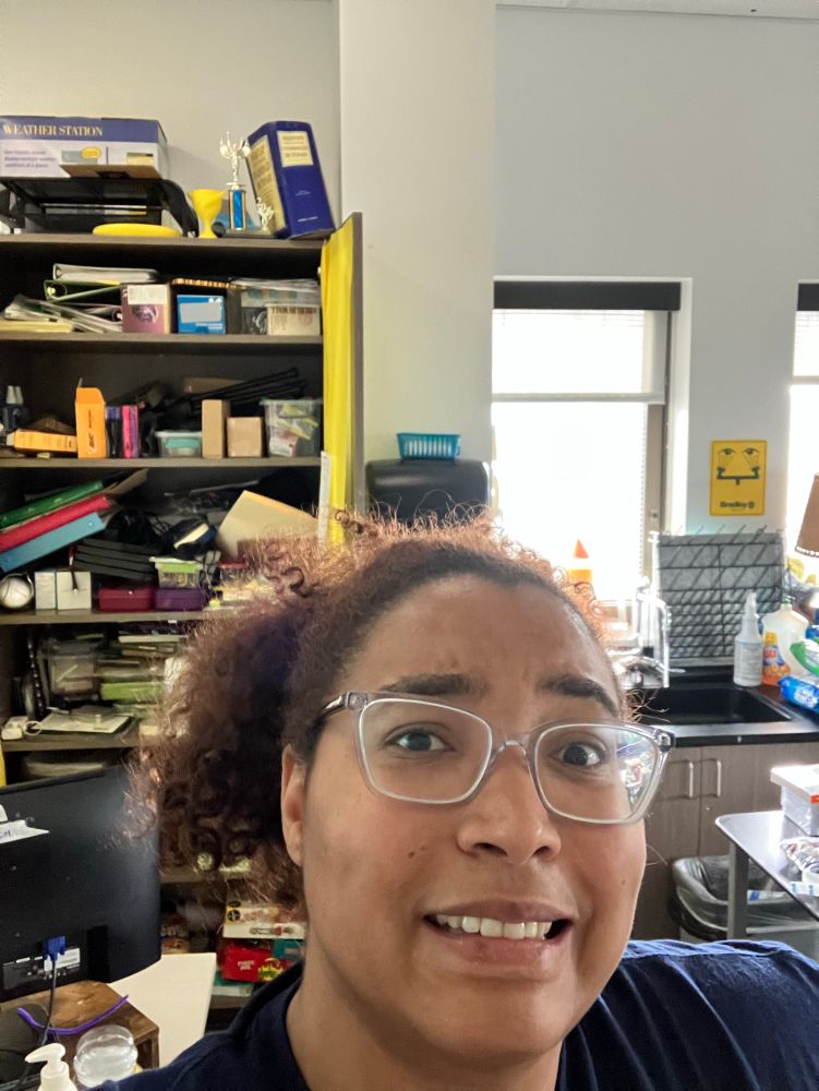 Me looking unsure in front of a messy ass cabinet in my classroom 