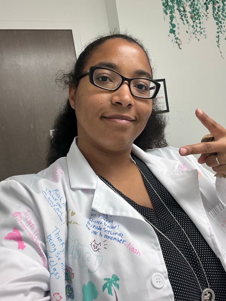 Me in my classroom throwing up a peace sign wearing the lab coat my students signed