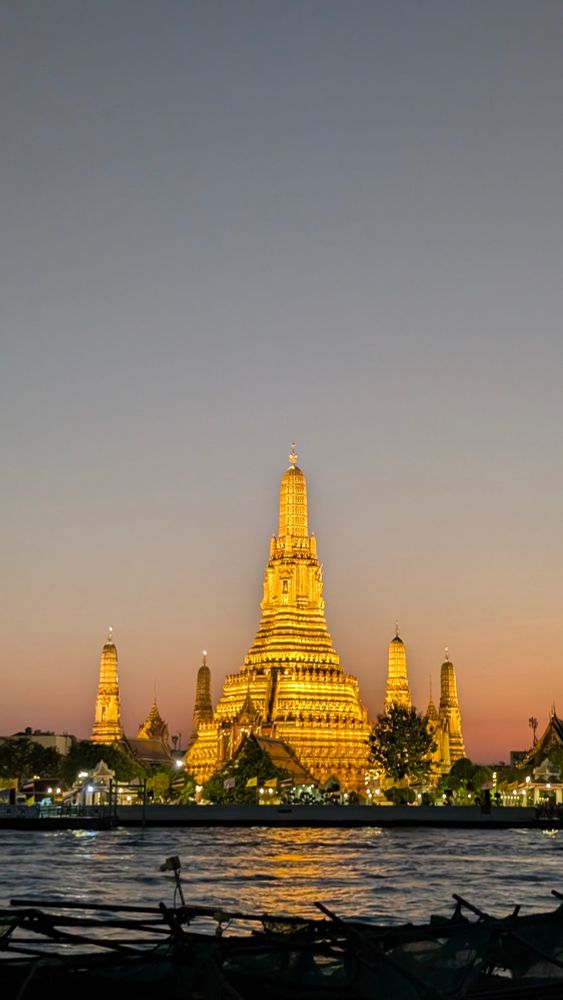 Wat Arun illuminated at dusk, showcasing stunning architecture against a twilight sky.
