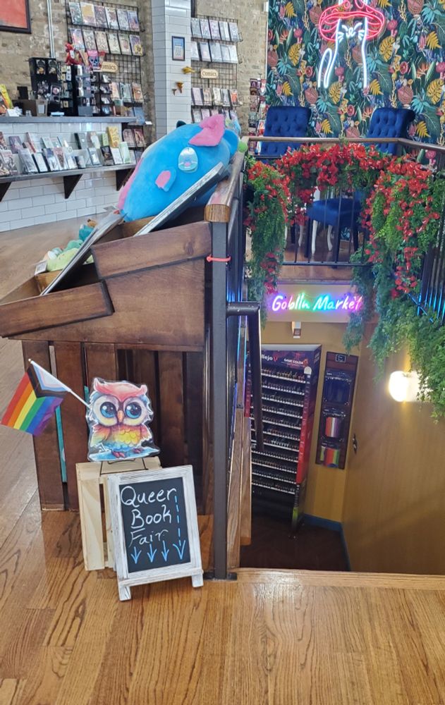 The stairs to Goblin Market's Art & Community space with a sign saying Queer Book Fair
