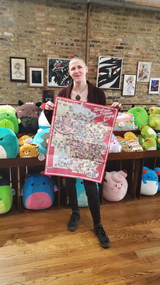 Ryvre of Goblin Market holding an unfolded poster with a map of the US Midwest