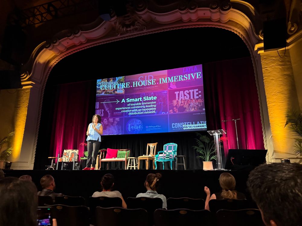A brunette woman stands on a proscenium stage with a slide behind her:

CULTURE. HOUSE IMMERSIVE

A Smart Slate of tourable immersive
experiences combining leading creative with an innovative
distribution network.

CULTURE HOUSE


How We Human Together – Mikhael Tara Garver (Culture House Immersive)

