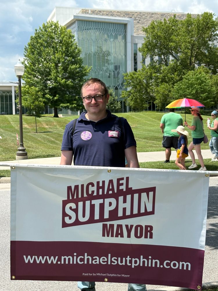 Michael in front of a Sutphin for Mayor banner